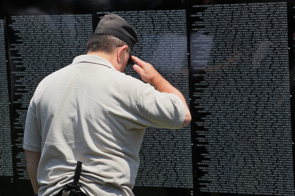 Dennis Lovick, who served in Vietnam with the Army from 1967 to 1969, salutes the name of a fallen friend inscribed on the Moving Wall display, a half-size replica of the Vietnam Veterans Memorial. (Photo: Scott Olson/Getty Images)