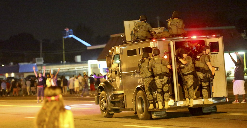 An armored vehicle carries police officers in tactical gear down West Florissant Avenue in Ferguson. (Photo: Timothy Tai/Newscom)