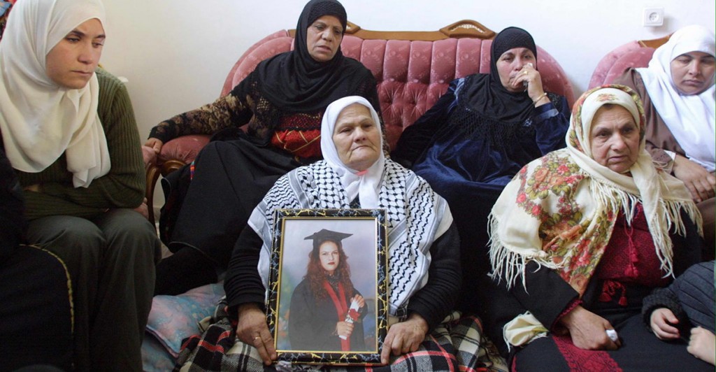 Wasfiyeh Idris, mother of suicide bomber Wafa Idris, surrounded by other female family members, holds a portrait of her daughter at her home in the al-Amari refugee camp near the West Bank town of Ramallah. According to evidence presented at a terrorism trial today, families of suicide bombers received payments about four times the average annual Palestinian income. (Photo: Awad/Newscom)