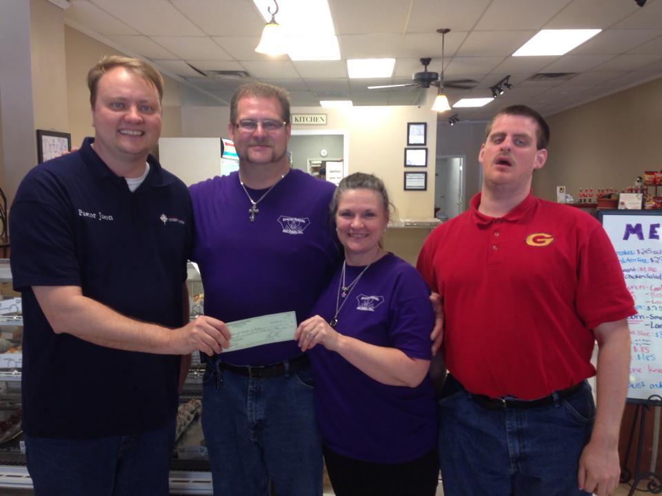 Pastor Jason from Amazing Grace church presents the bakery with a donation from their Lent offering. 