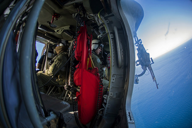 An MH-60S air crewman with Helicopter Sea Combat Squadron 28, Iwo Jima Amphibious Ready Group, gazes out of the gunner's door of a Seahawk helicopter while participating in flight operations over the Atlantic Ocean. (Photo: Cpl. Todd F. Michalek/Released)