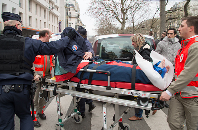 An injured person gets carried away from the site by a stretcher outside the Charlie Hebdo office. (Photo: Lionel Urman/Newscom)