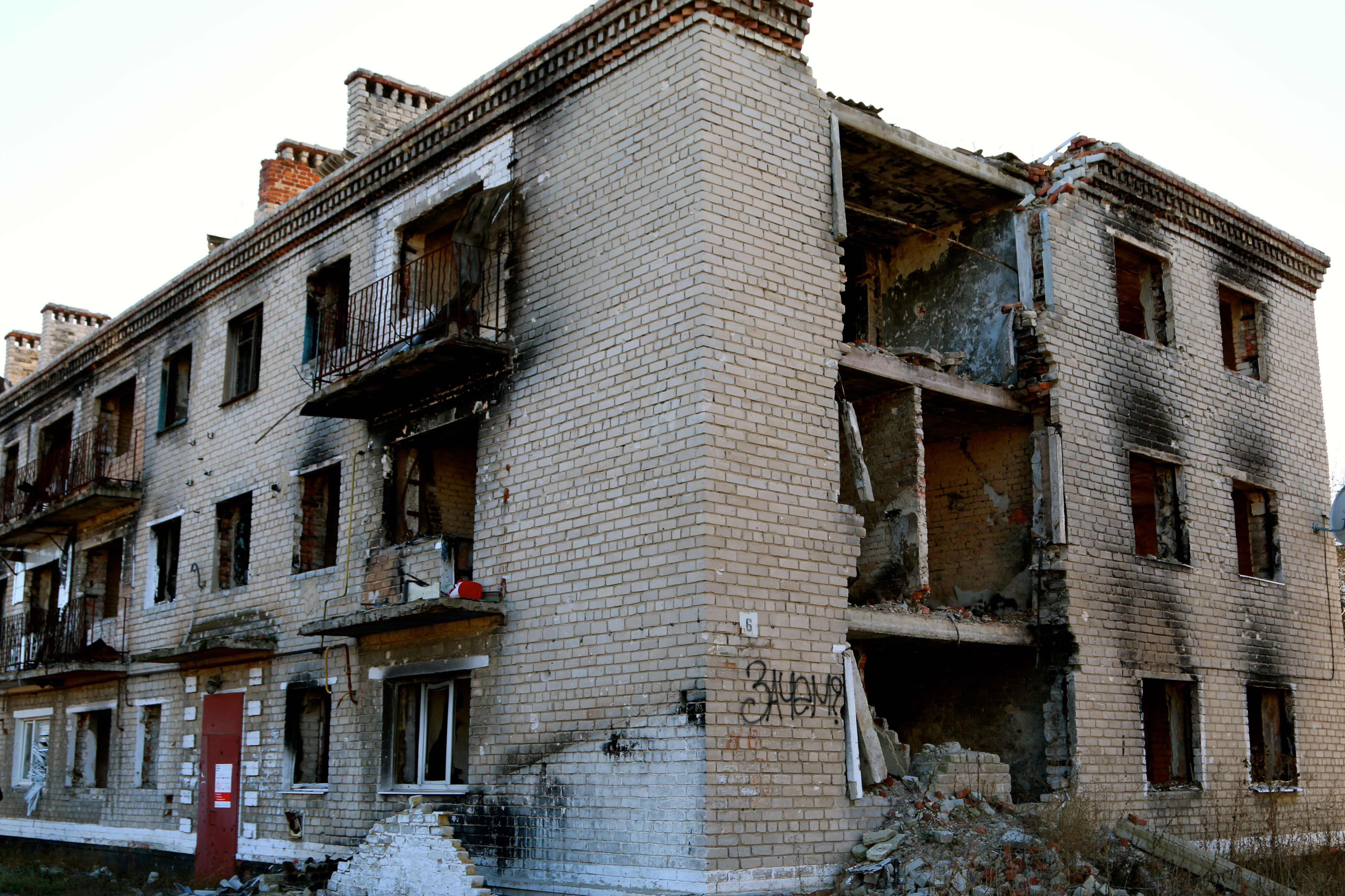 An artillery-blasted apartment building in Marinka is marked by a spray-painted word in Russian, which translates to “For what?”