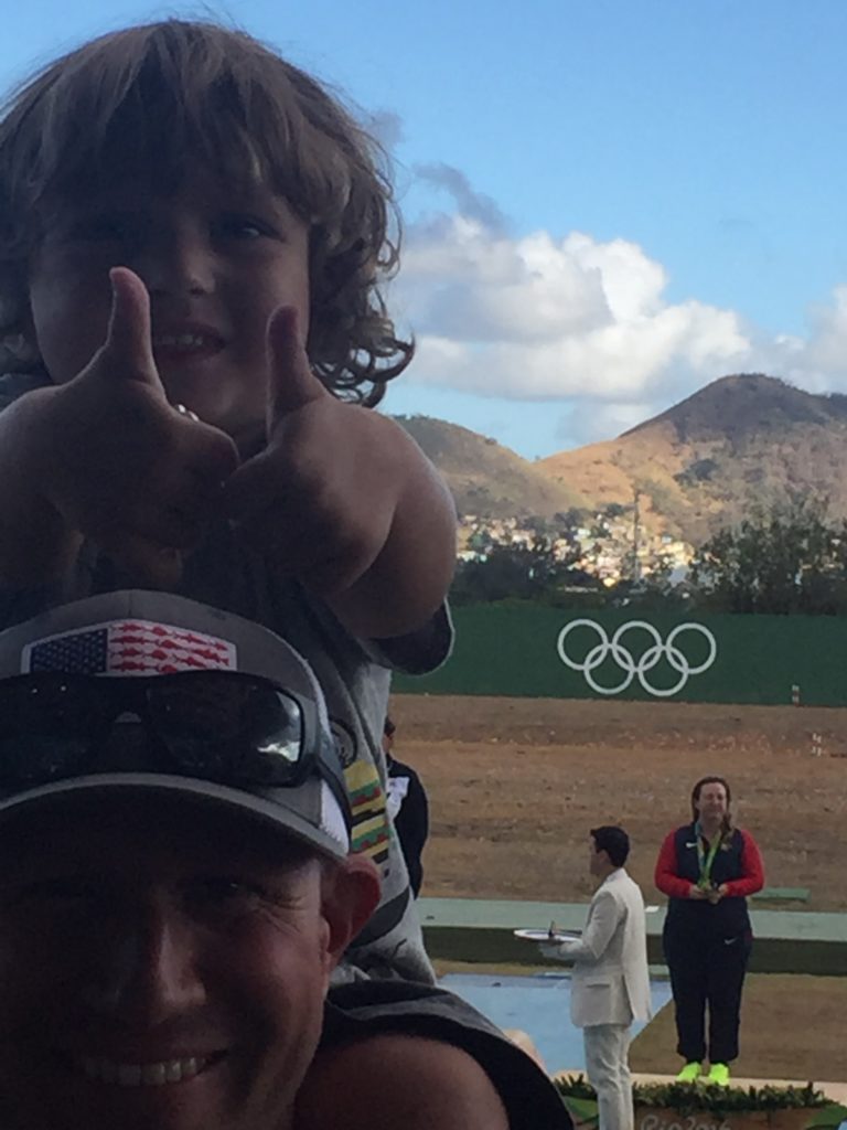 Kim Rhode's husband, Mike Harryman, poses with their 3-year-old son as Rhode is awarded a bronze medal. (Photo: Kim Rhode)