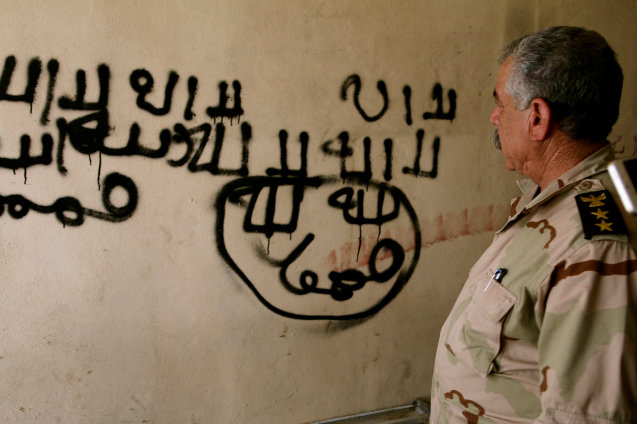 Peshmerga Col. Shuqur Qasim Yusif in front of ISIS graffiti.