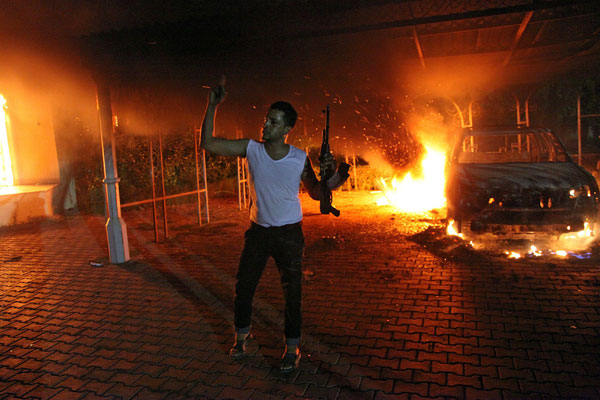 An armed man waves his rifle as buildings and cars are engulfed in flames after being set on fire inside the US consulate compound in Benghazi late on Sept. 11, 2012. (Photo: Getty Images/Newscom)