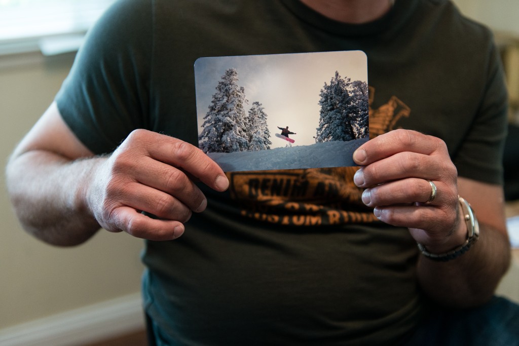 Anthony R. Orefice holds a photo of himself snowboarding at Mt. High in California before his accident.  Orefice says he is still physically active despite being paralyzed from the chest down. (Photo: Heidi de Marco/KHN)