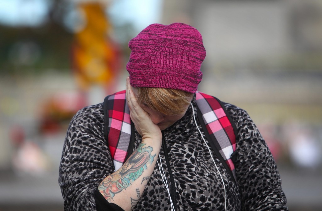 A woman wipes away tears after paying her respects for the dead soldier at the War Memorial in Ottawa, Canada, 23 October 2014. 
