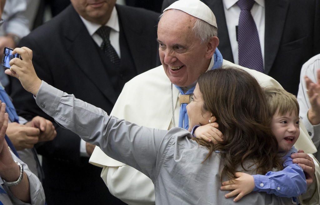 Pope Francis poses for a 'selfie' with a mother and her child. (Photo: Newscom)