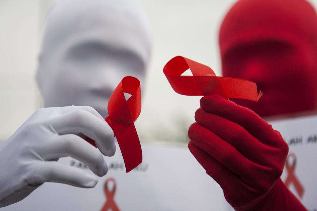 Indonesian activists wear masks and hold red ribbons during an AIDS day campaign. (Photo: Fully Handoko/Newscom)