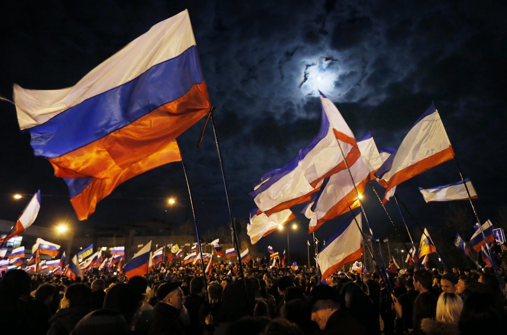 People holding Russian and Crimean flags as they gather at Lenin Square after the end of the referendum in Simferopol, Crimea March 16, 2014. (Photo: Yuri Kochetkov/Newscom)