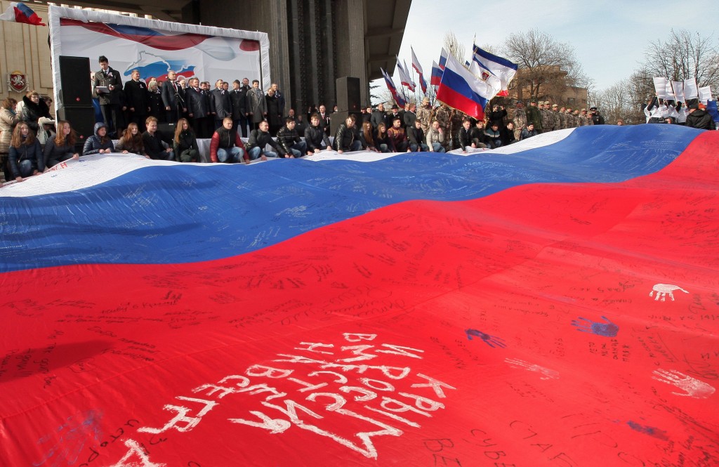 Crimean people spread a huge Russian flag with white words in it saying 'Russia Crimea Together Forever' and  inhabitants' inscriptions during a rally to mark  anniversary of controversial referendum to join Russia, in Simferopol, Crimea, March 16, 2015. (Photo: Artur Shvarts/Newscom)