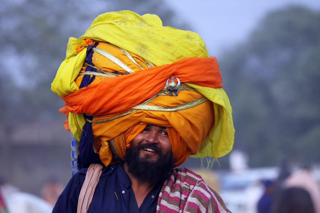 An Indian 'Nihang' or a man whose ancestors belonged to Sikh warrior clan, smiles supporting an over-sized turban as he takes part in a religious procession called Mohalla in Amritsar, India. (Photo: Newscom)