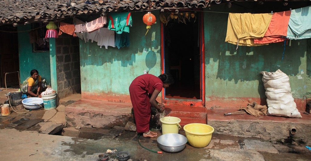A slum woman in India washes clothes from the  tap  water in the Slum neighbourhood at Belgaum. [Photo via Newscom]
