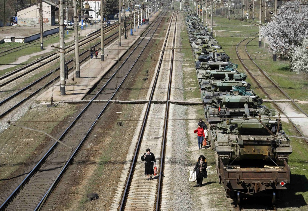 Local commuters walk along railway lines next to Ukrainian tanks ready to depart from Crimea to Ukraine March 31, 2014. (Photo: Yannis Behrakis/Newscom)