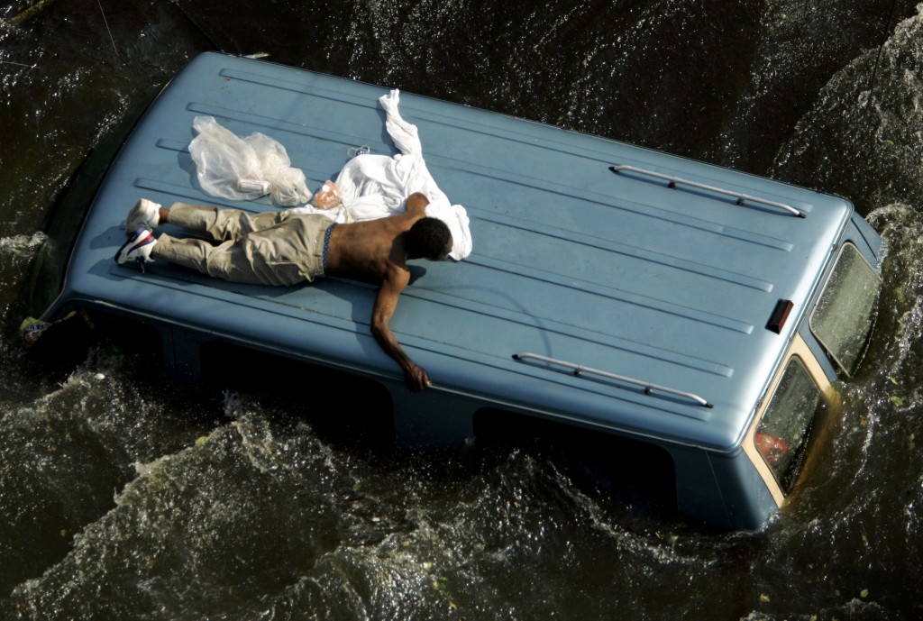 A man clings to the top of a vehicle before being rescued by the U.S. Coast Guard from the flooded streets of New Orleans, six days after the hurricane struck the city. (Photo: Robert Galbraith/Reuters/Newscom)
