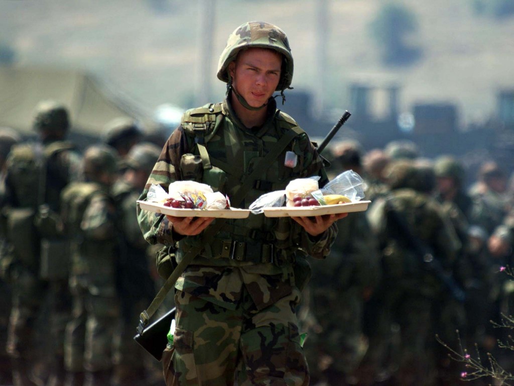 A U.S. marine carries food from a barbeque celebrating July 4 while on tour in Yugoslavia, 1999. (Photo: Laszlo Balogh/ Reuters/Newscom)