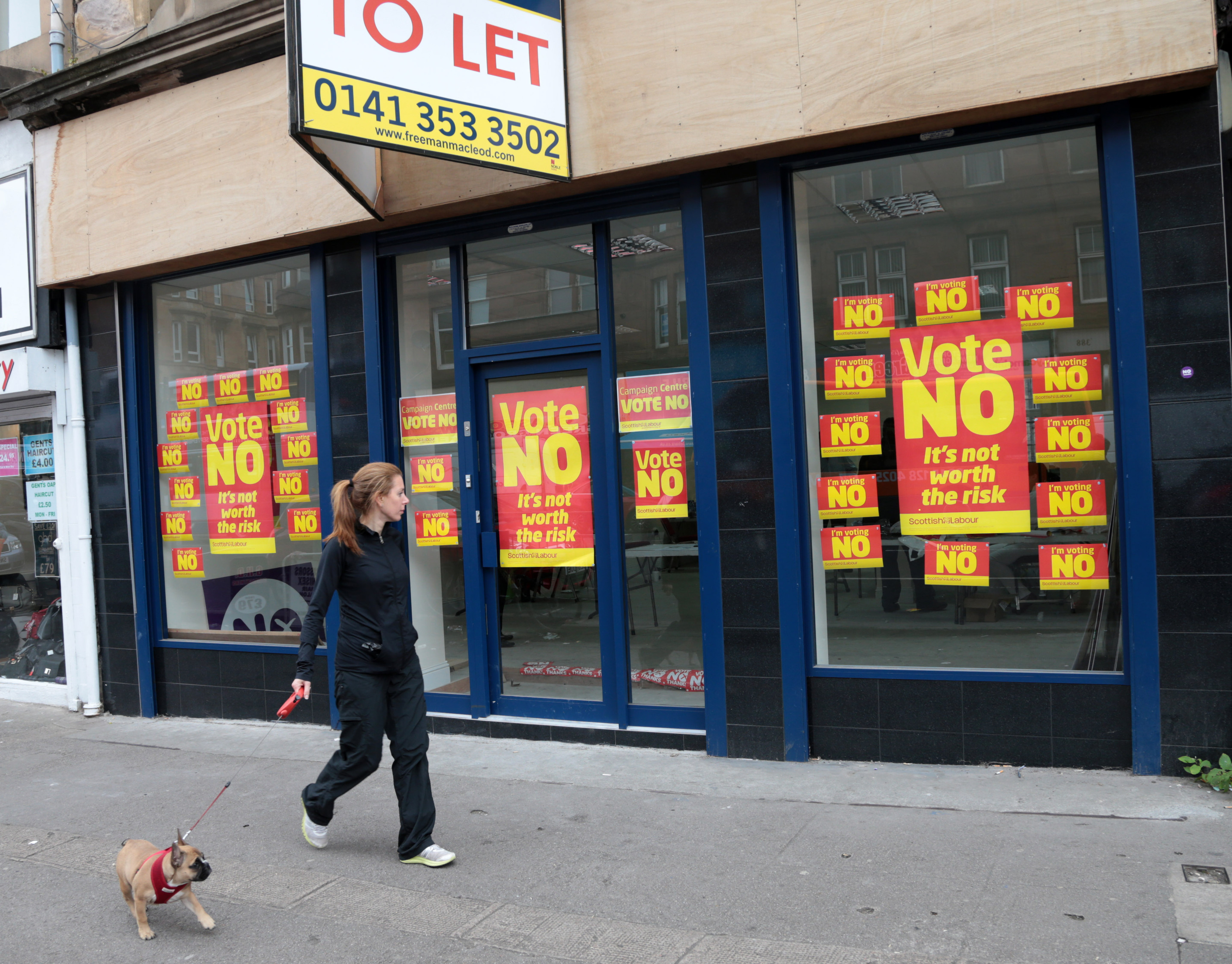 A lady walks past a building with a large number of "No Vote" posters against Independence on the day Scottish residents vote.