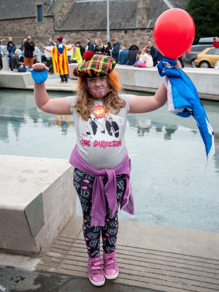 A child dressed Scottish hat and red wig outside the Scottish Parliament.