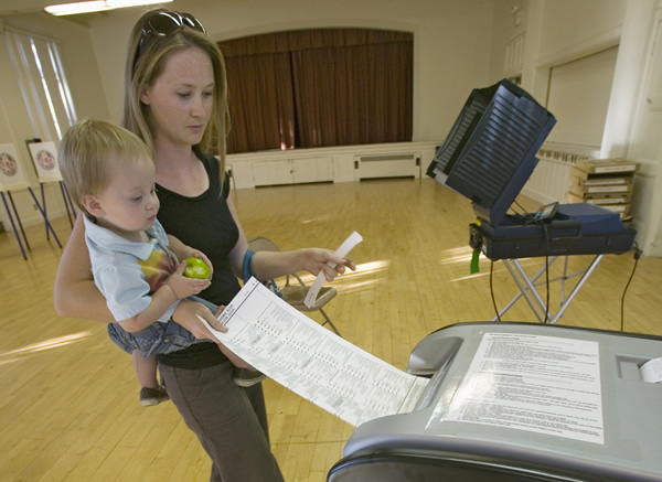 Young mother and baby inserts completed ballot for Congressional election