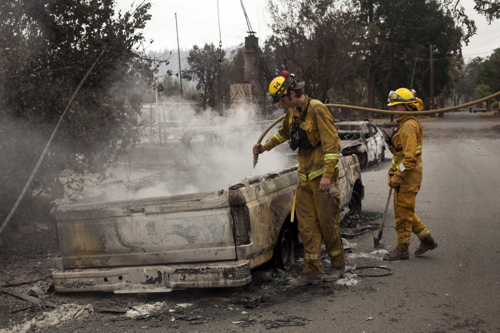 Firefighters extinguish a flare up in an automobile burnt by the Valley Fire near Middletown, California, September 14, 2015.  (Photo: REUTERS/David Ryder/Newscom)