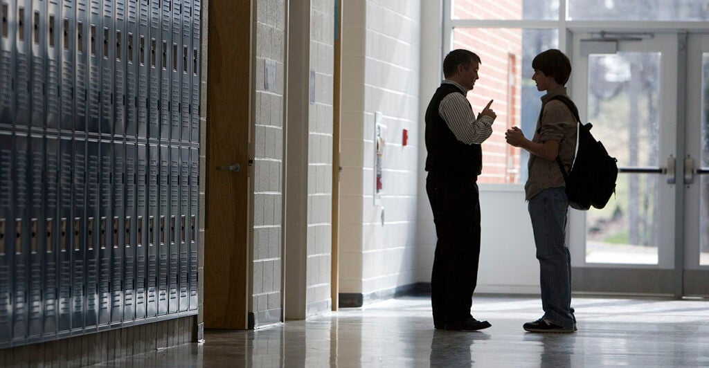 High School Teacher and Student Talking in Hallway