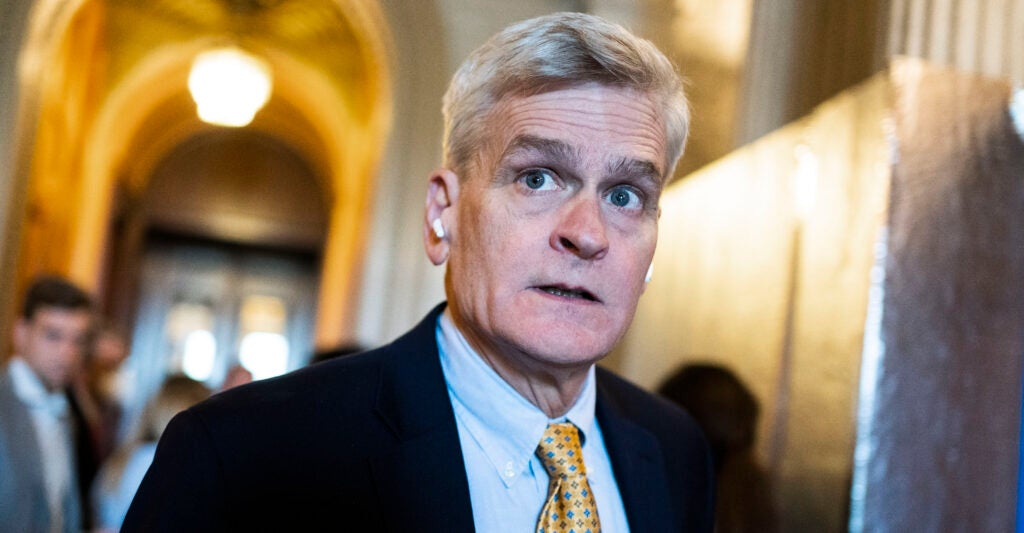 White man in suit and tie with white hair in hallway