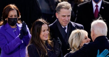 Hunter Biden in a suit looks on as Jill Biden embraces Joe Biden and Kamala Harris in a blue pantsuit claps enthusiastically