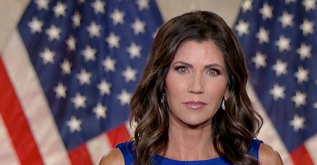 Kristi Noem in front of American flags