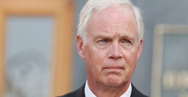 Elderly white man scowls in a suit and white hair