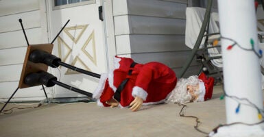 A statue of Santa Claus falls over in front of a house