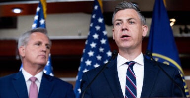 Jim Banks and Kevin McCarthy in suits in front of American flags