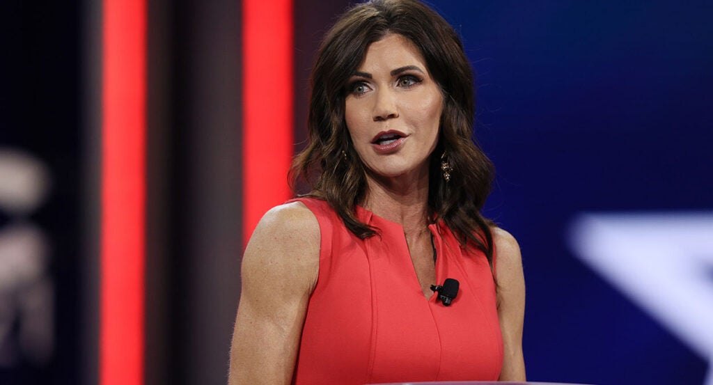 Kristi Noem in a red dress speaks at CPAC