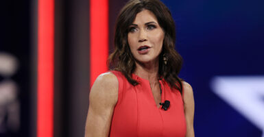 Kristi Noem in a red dress speaks at CPAC