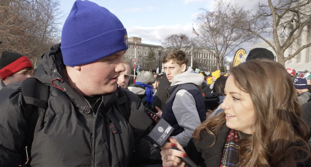 Mary Margaret Olohan in a coat interviews student wearing a coat and beanie