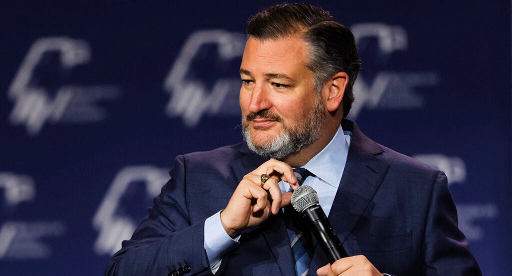 Ted Cruz in a blue suit checks his microphone