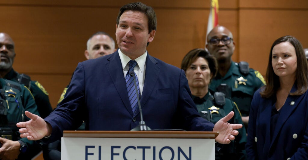 Ron DeSantis speaks at a podium in a suit