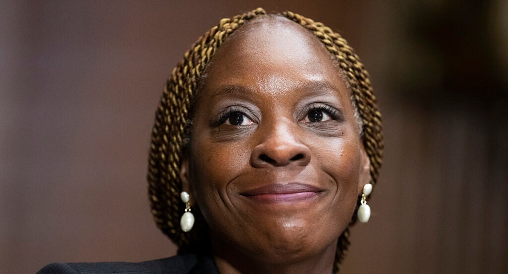 Black lady smiles with white earrings and braided blonde hair