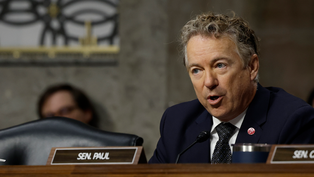 Rand Paul in a suit behind a name tag