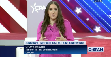 Chaya Raichik speaks in front of a CPAC logo