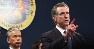 Gavin Newsom in a suit speaks in front of the California seal