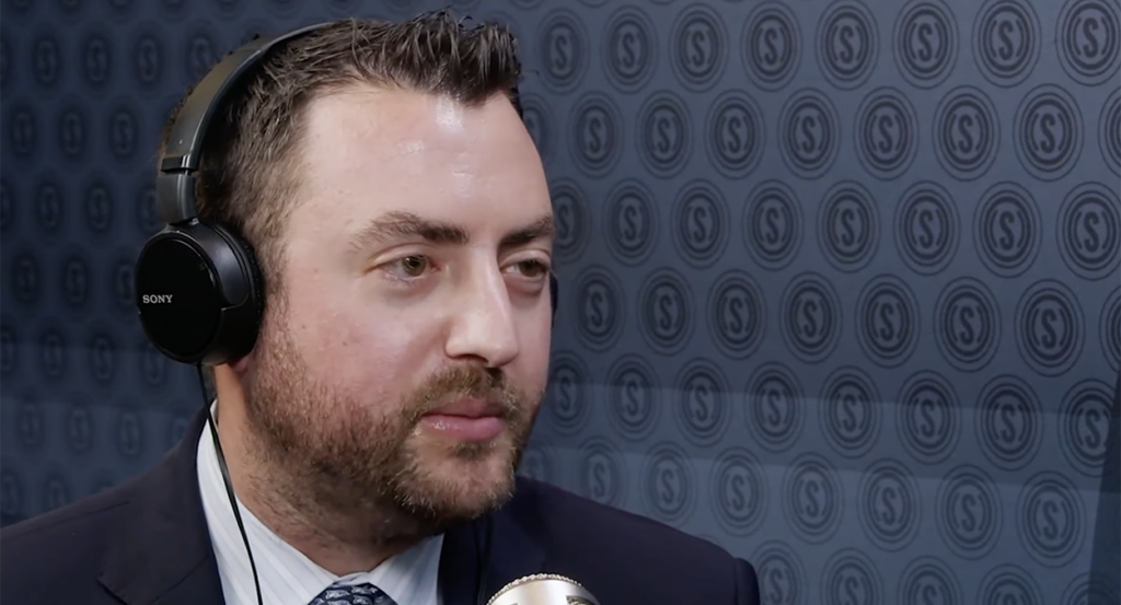 Newsweek Opinion Editor Josh Hammer with the Daily Signal logo behind him.