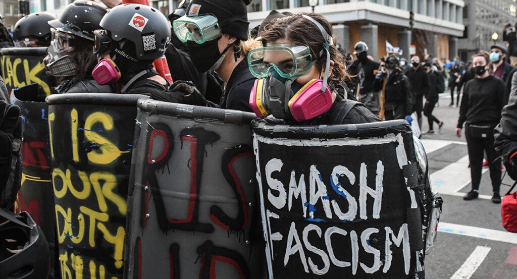 Antifa agitators march with shields and helmets in the street