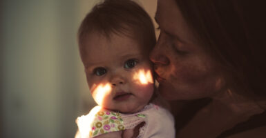 A mother kisses her her baby's cheek.