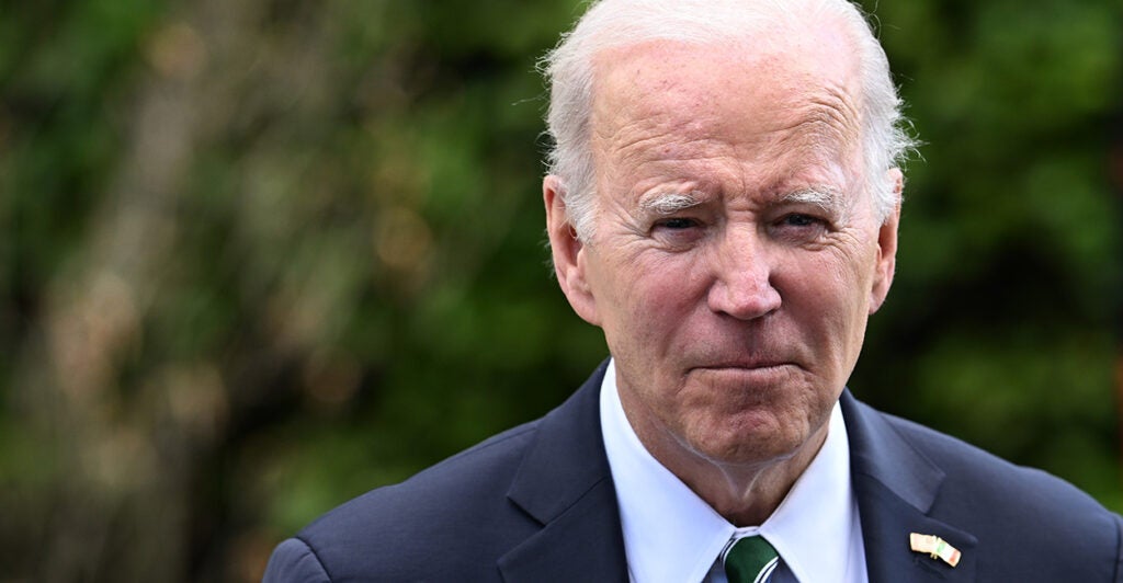 President Joe Biden in a suit walking outside.