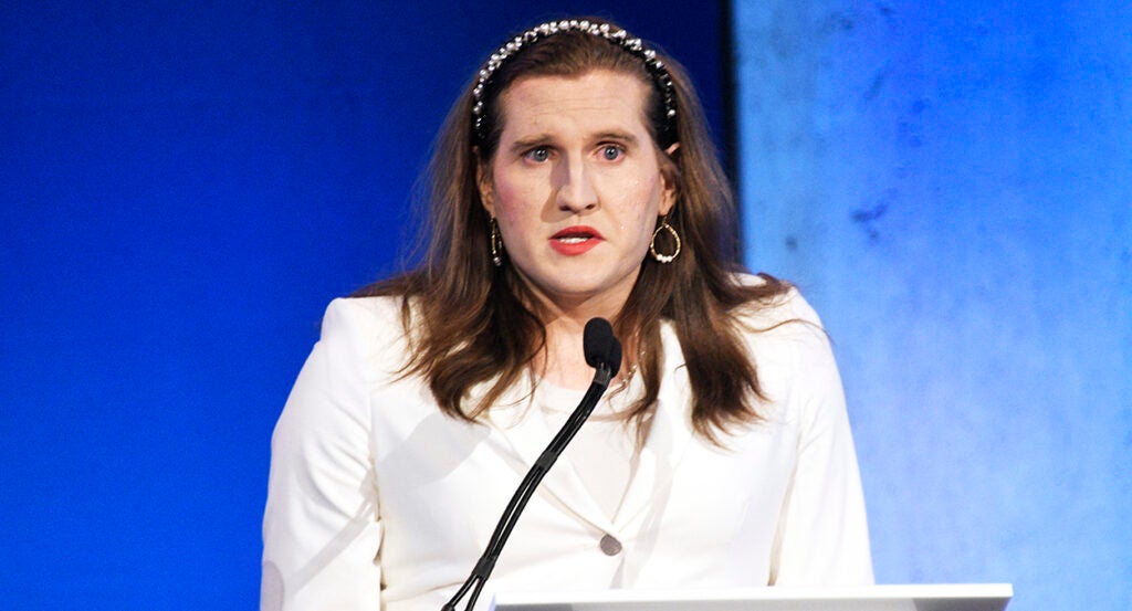 Charlotte Clymer in a white suit before a blue background