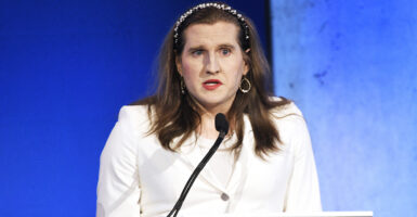 Charlotte Clymer in a white suit before a blue background