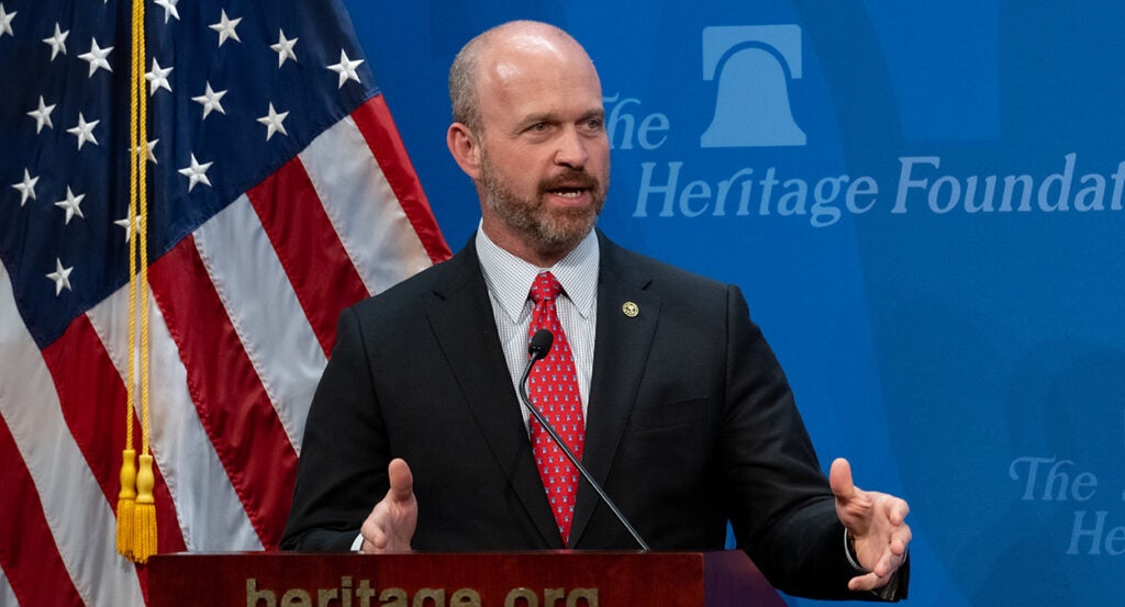 Heritage President Kevin Roberts in a suit in front of an American flag