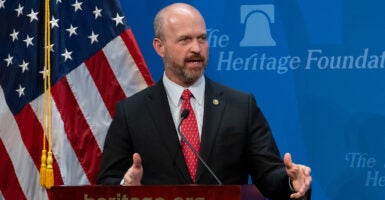 Heritage President Kevin Roberts in a suit in front of an American flag