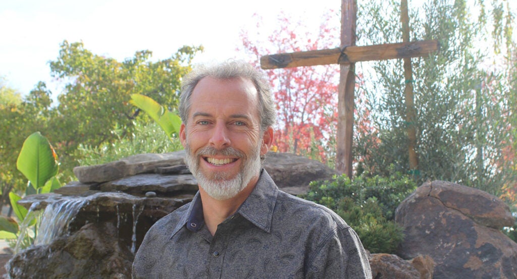 Pastor Mike McClure stands in front of a cross